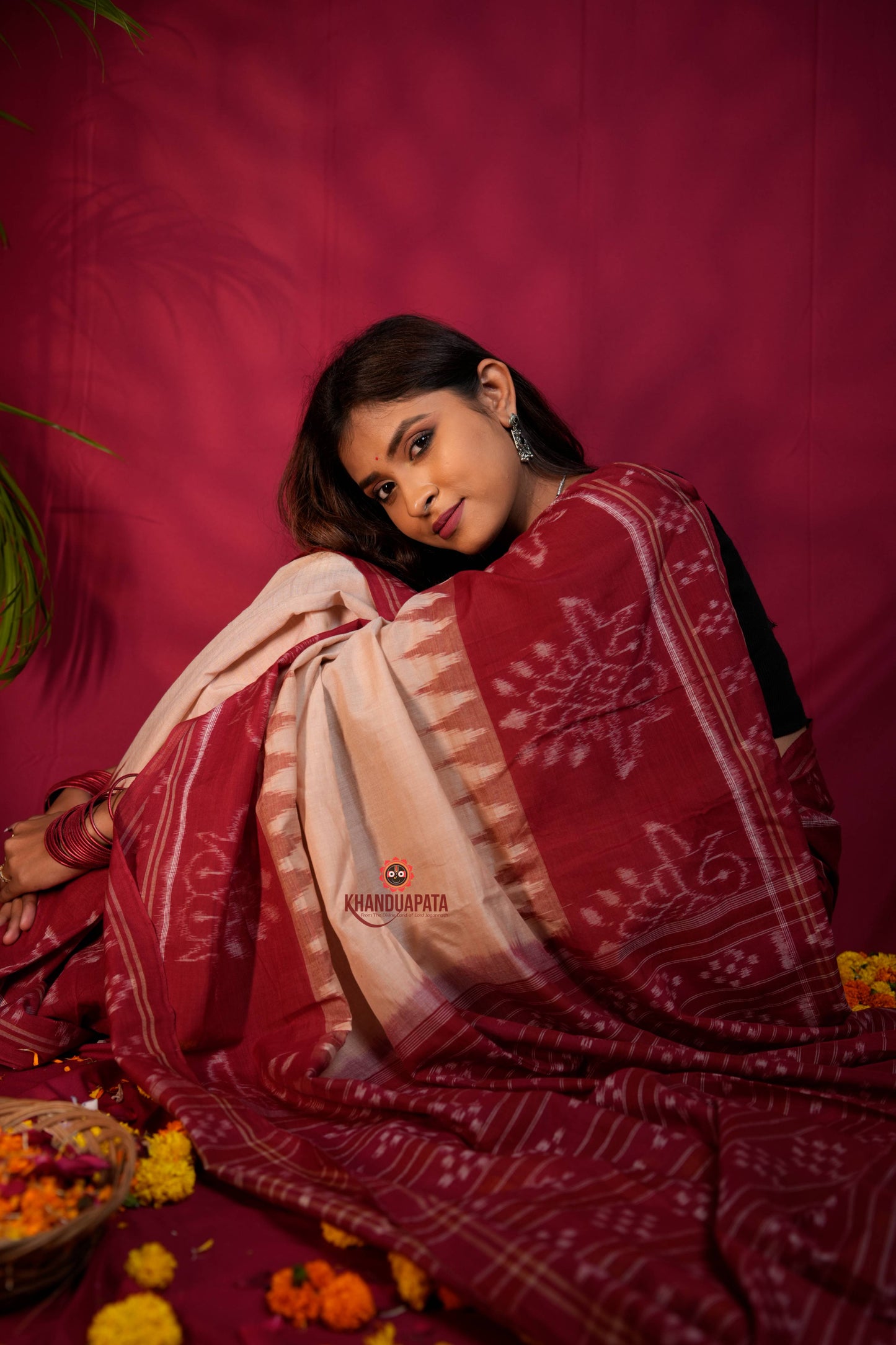Woman in a red and white saree with a pink background