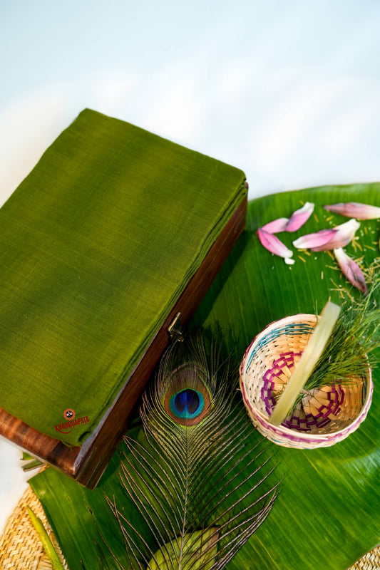 Green fabric with a peacock feather and a small bowl on a banana leaf