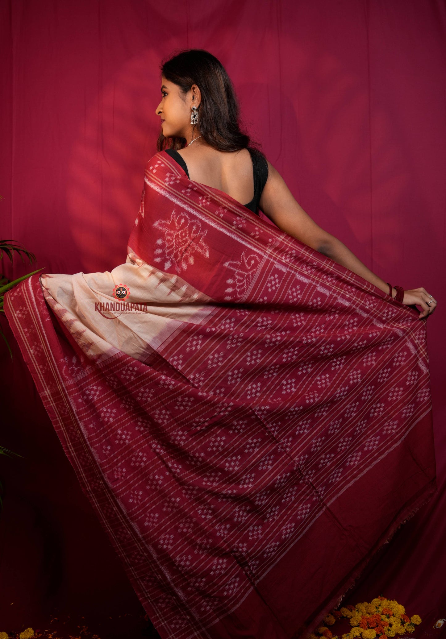 Woman wearing a red and white patterned saree against a red background