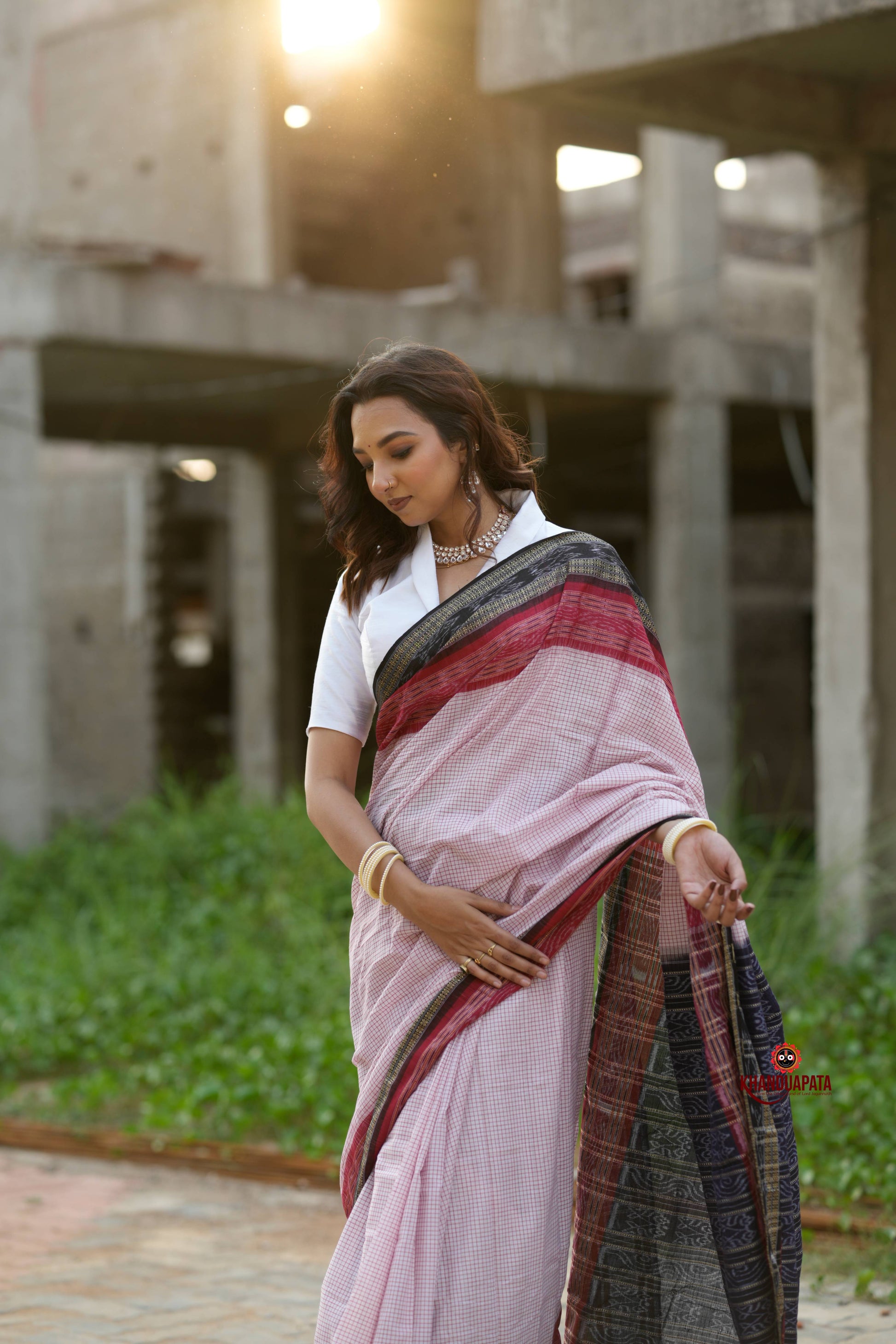 Woman in a saree standing outdoors with a building in the background