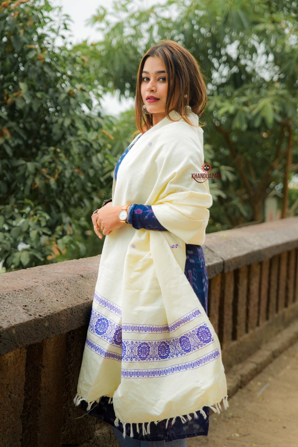 Woman wearing a cream-colored shawl with blue patterns outdoors