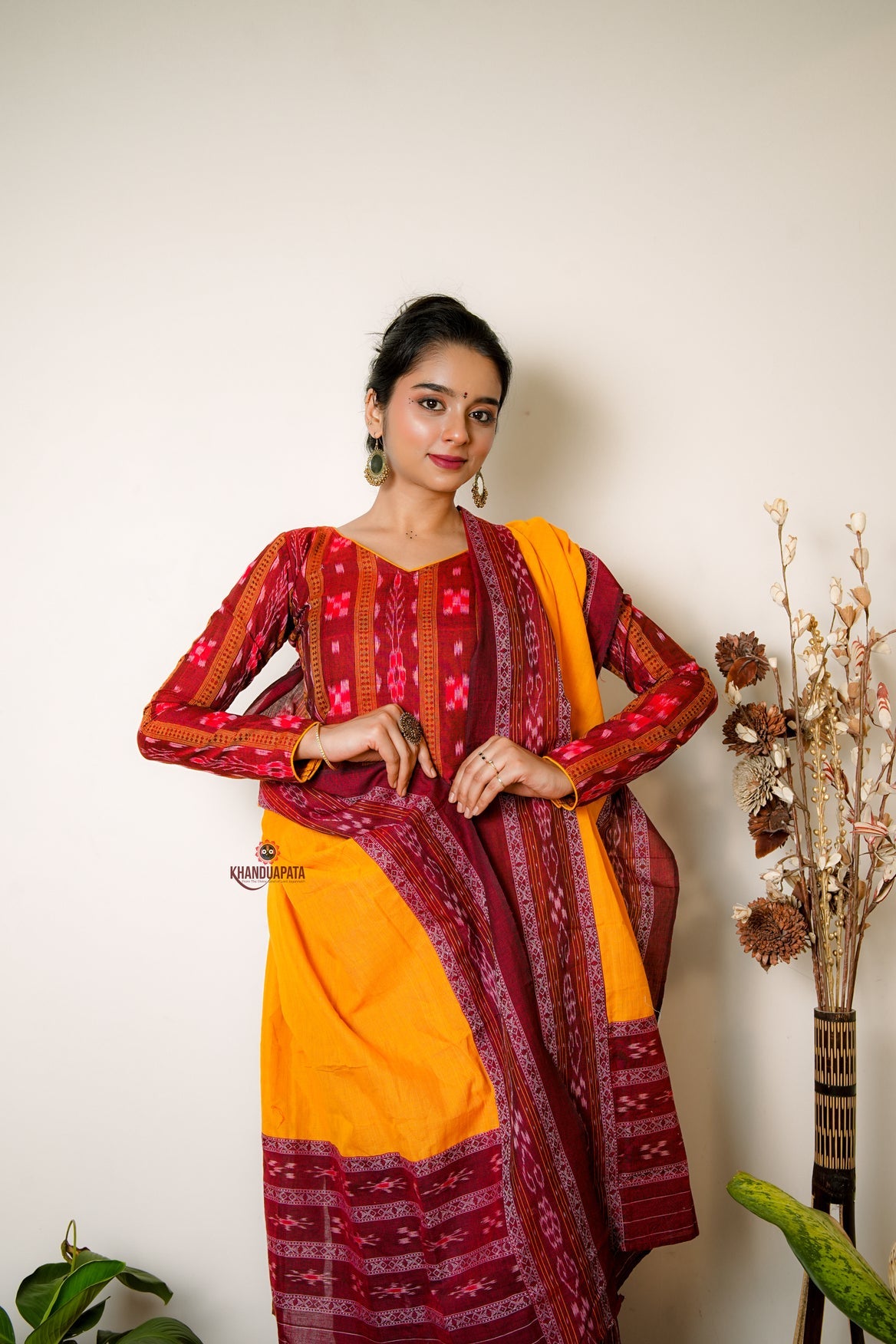 Woman wearing a traditional outfit with red and yellow patterns against a white background