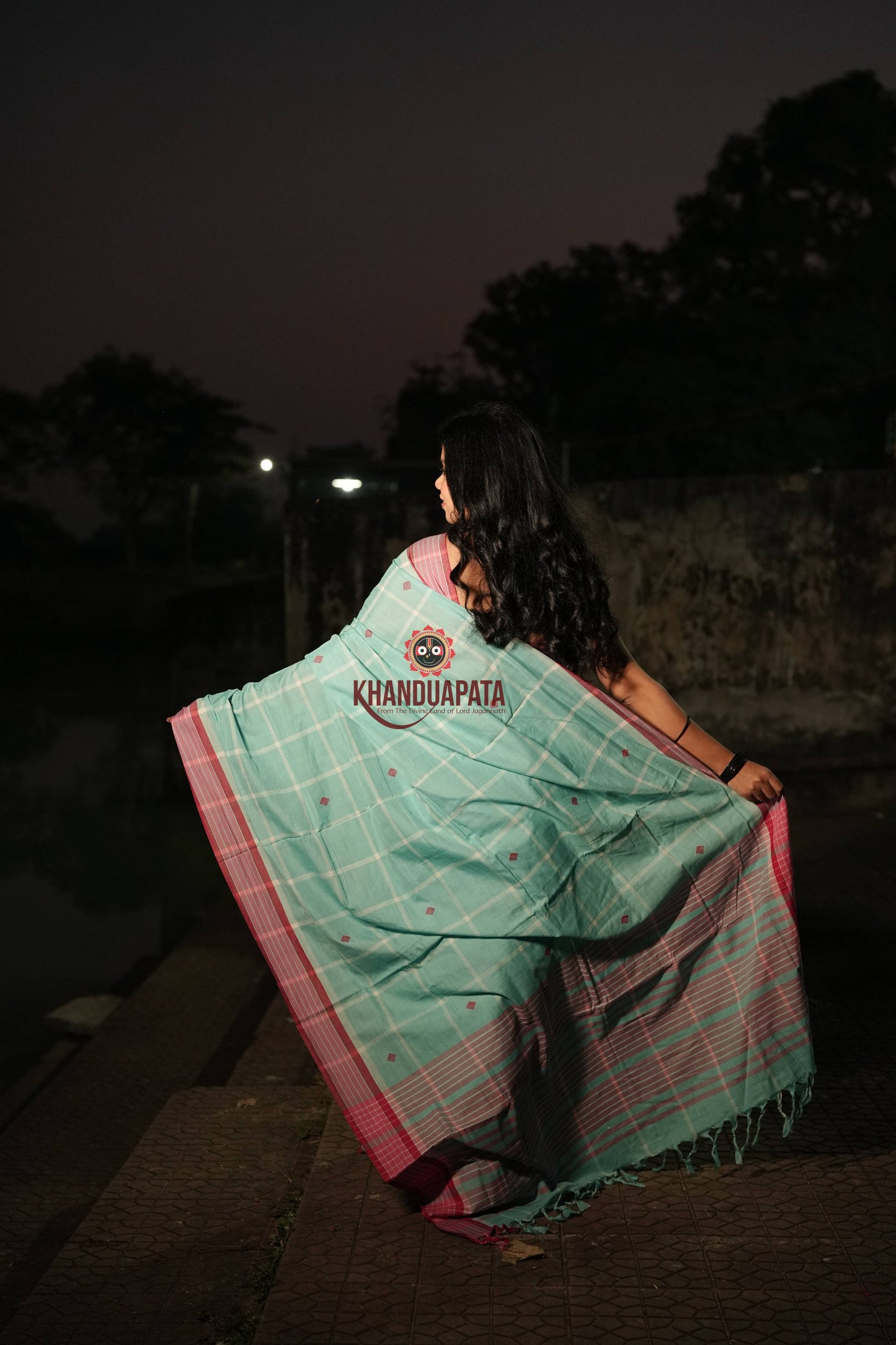 Woman wearing a Khandua Pata saree at night with trees in the background