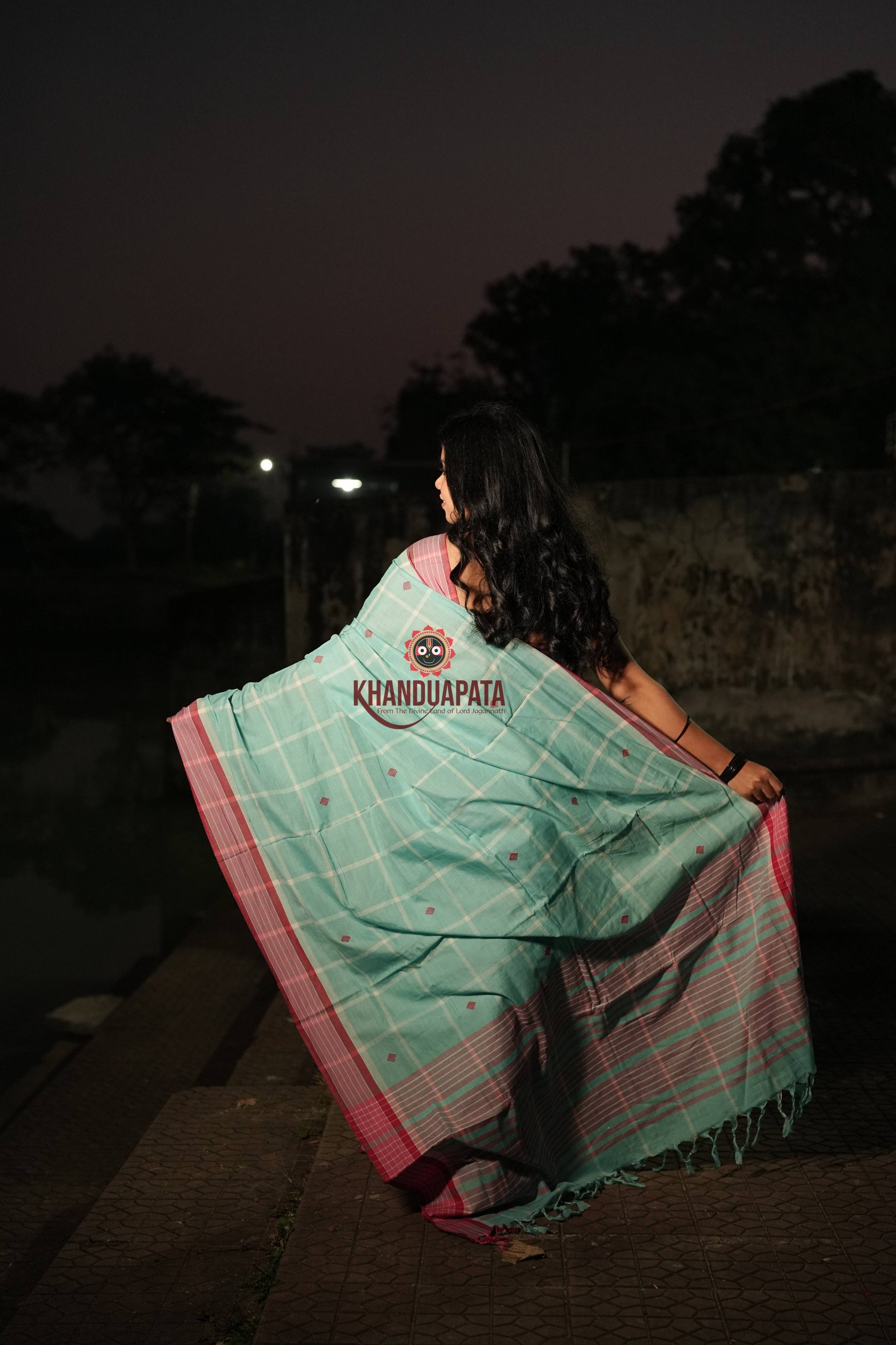 Woman wearing a Khandua Pata saree at night with trees in the background