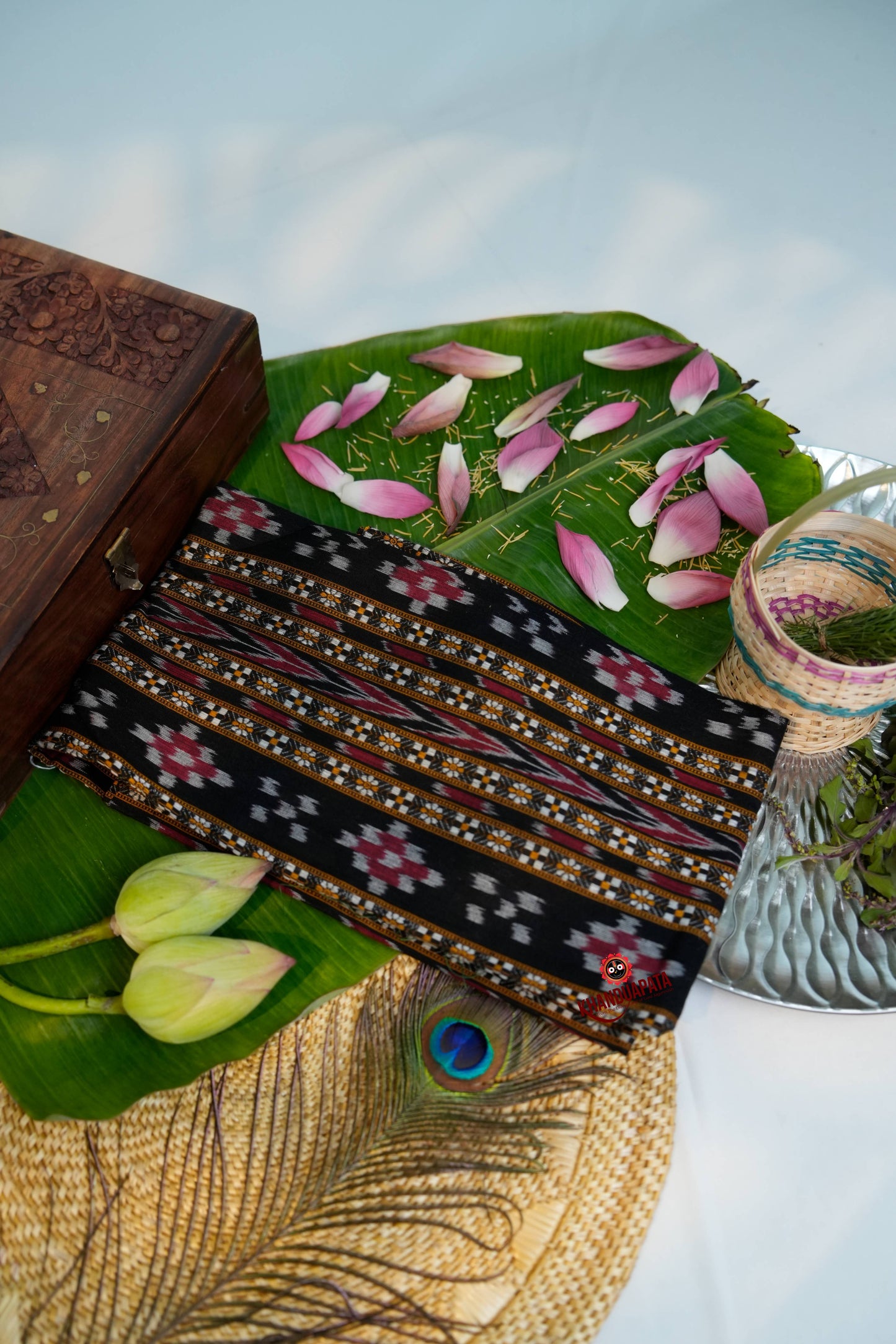 Decorative items including a wooden box, patterned fabric, and flowers on a table with a blurred background.