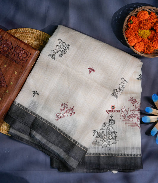 White saree with black and red embroidery on a blue fabric background
